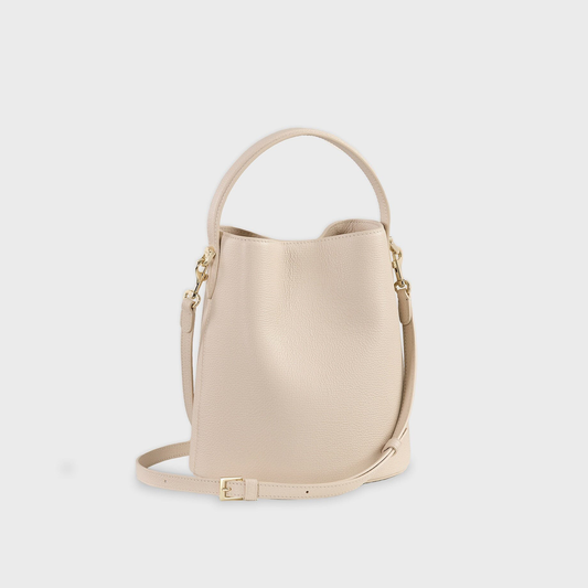 Soft Mushroom Cream Fine Grain Tapered Bucket Hand Bag With Oval Magnetic Clasp, Curved Top Grip And Detachable Slim Shoulder Strap